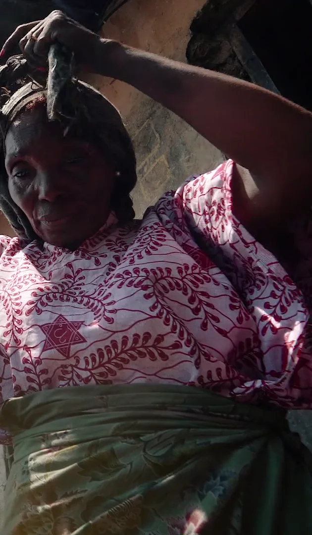 Maman Kungu ajuste sa charge sur la tête avant de partir