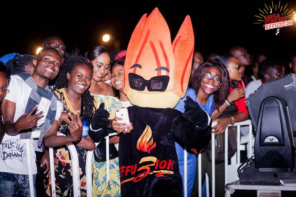 La mascotte flamme pose avec le public derrière les barrières. Photo de l’événement Effuzion.