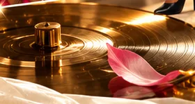 Détail de composition éditoriale : vinyle doré et pétale rose. Visuel conceptuel.