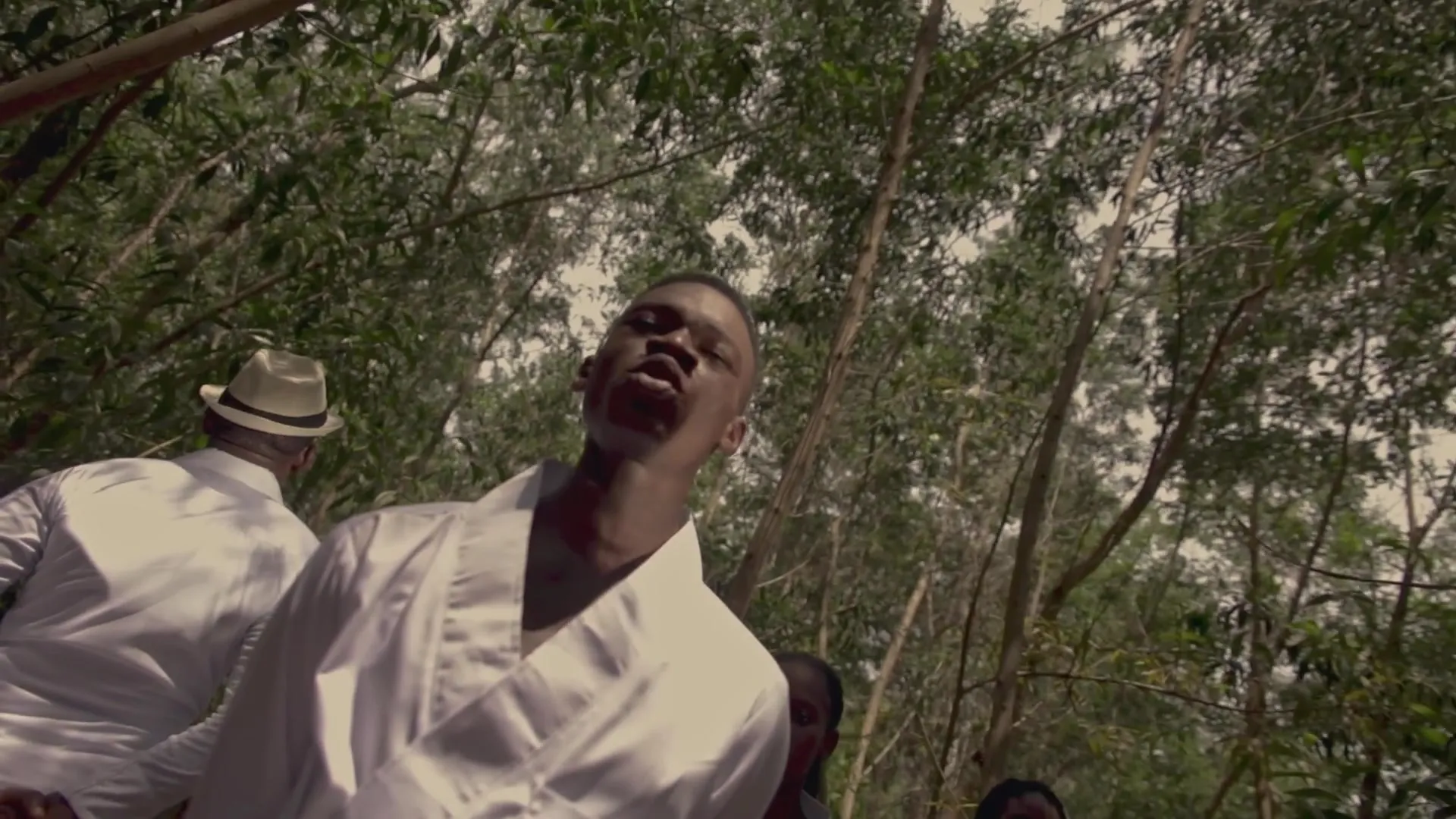 Contre-plongée : un chanteur en blanc, la tête en arrière. Image extraite du clip officiel.