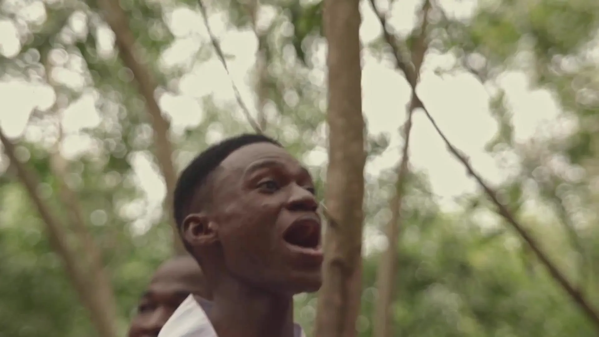 Gros plan sur un chanteur en blanc, bouche ouverte. Image extraite du clip officiel.