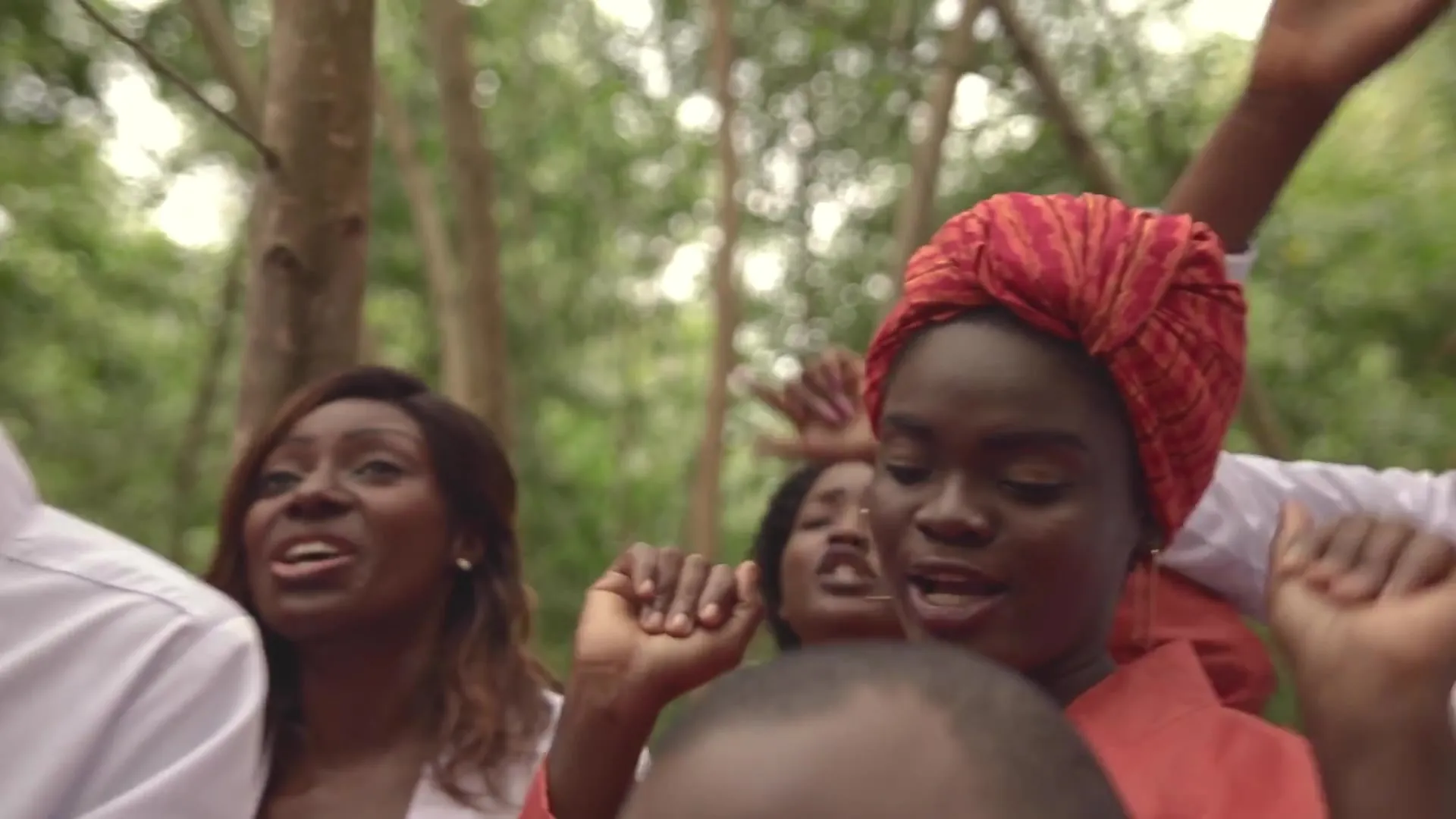 Une chanteuse au foulard rouge, entourée du chœur. Image extraite du clip officiel.