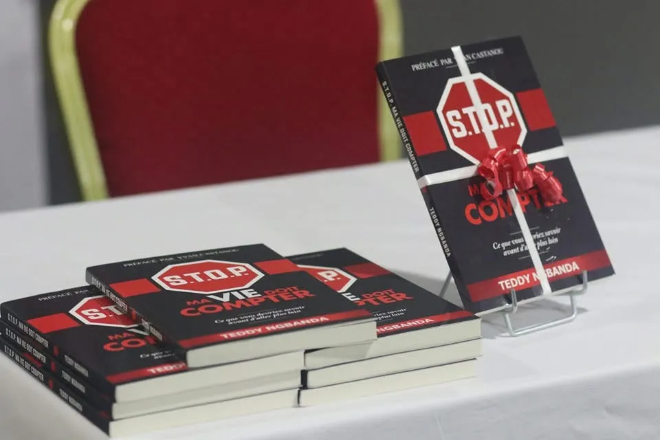 Des piles du livre S.T.O.P. sur une table, un exemplaire debout. Photo de terrain de la campagne.
